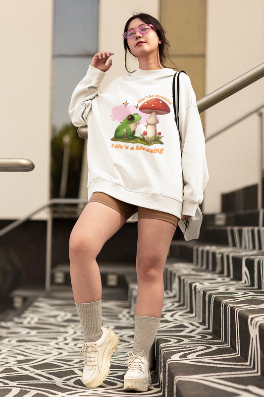 young woman wearing a cottage core inspired hoodie with a frog sitting under a mushroom design on it